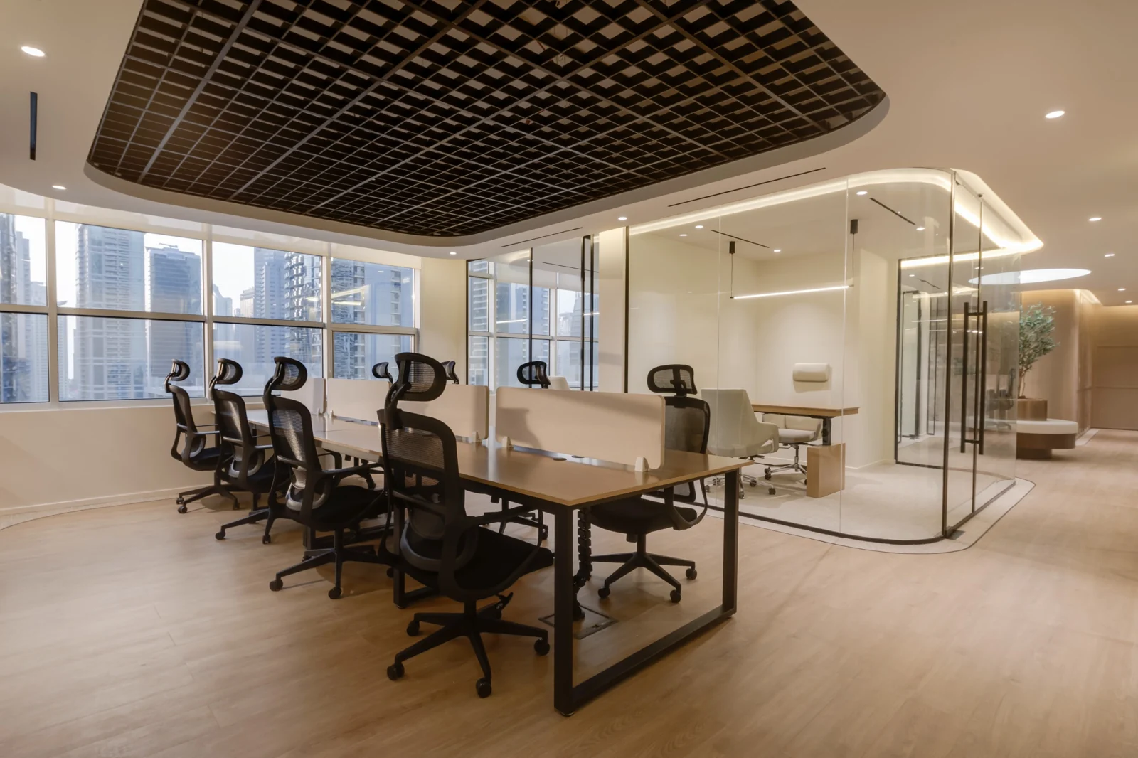 A suspended black grid frames the shared desks, with glazing keeping the adjoining rooms in view.
