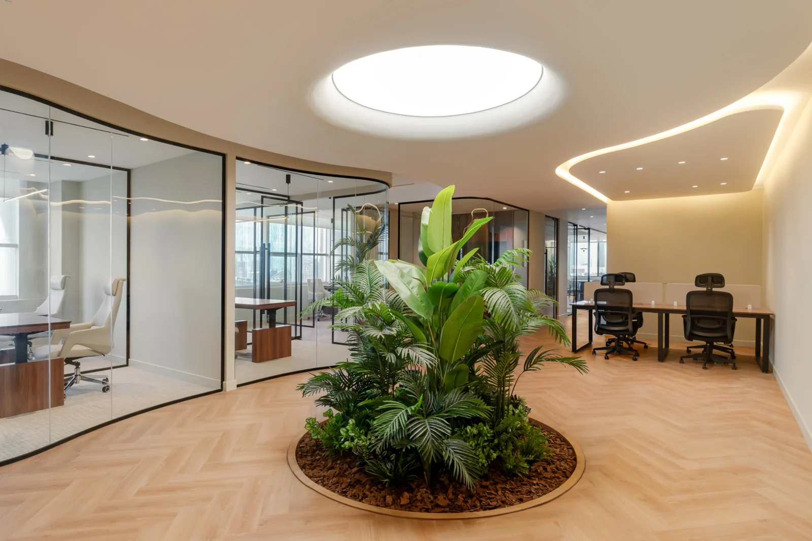 A circular planted bed sits within the herringbone floor, with curved glass rooms opening around it.
